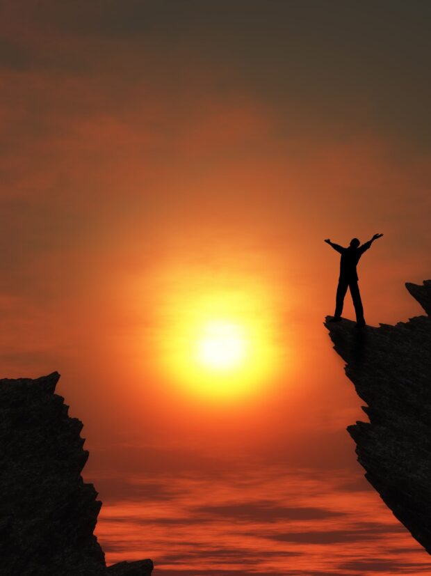 D render of a man stood on a mountain top with arms outstretched